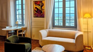 Un salon avec un canapé, une table ronde, une chaise, une lampe et un tableau.