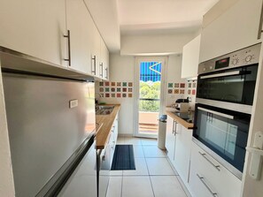 A modern kitchen with stainless steel appliances, a built-in oven, and a view through the door. - NEW: A favorite on the French Riviera—2-bedroom apartment with air conditioning, in a quiet part of downtown (Antibes)