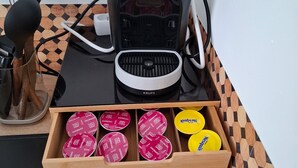 A coffee machine with a tray of coffee pods, sugar packets, and a box of Lipton tea bags. - Studio in the Drôme Provençale. Suze's Cocoon. (Suze-la-Rousse)