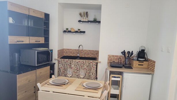 A compact kitchen with a microwave, a small refrigerator, a dining table with chairs, a sink, and a coffee machine. - Studio in the Drôme Provençale. Suze's Cocoon. (Suze-la-Rousse)