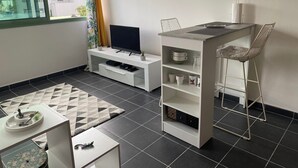 Una sala de estar moderna con televisor, una pequeña barra y una mesa de comedor.