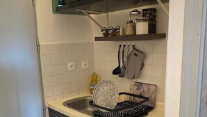 Cocina compacta con microondas, tostadora y escurreplatos en la encimera.