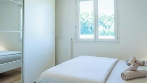 A bedroom with a bed, a window, and a mirror. - Maison des Pralets I T4 I Etrembières (Étrembières)