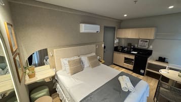 Habitación de hotel con cama, mesita de noche y una pequeña kitchenette.