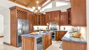 A kitchen with wooden cabinets, a stainless steel refrigerator, a built-in oven, and a granite countertop. - **LA BELLA CAPRI @ CASA MARINA** Estate & Pool + Last Key White Glove Service... (Key West)