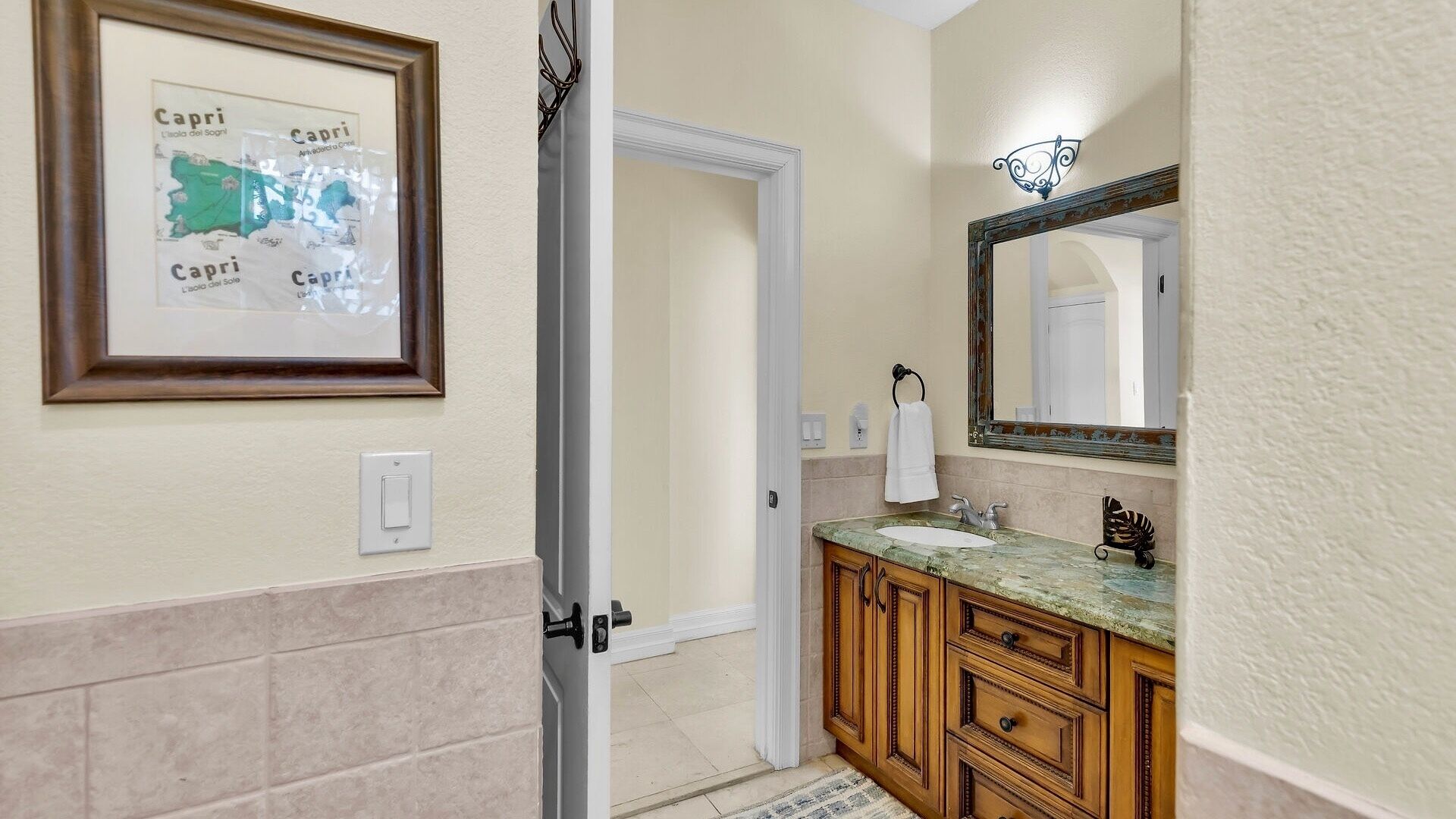 A bathroom with a framed map, a sink with a mirror, and wooden cabinets.