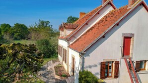 A narrow stone pathway leading to a row of traditional buildings with red-tiled roofs and white walls. - CHAMBERAT COUNTRY HOUSE (Chambérat)