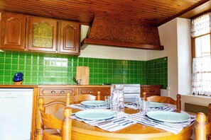 Eine Küche mit grünen Fliesen, Holzschränken und einem Esstisch, gedeckt mit Tellern, Gläsern und Besteck.
