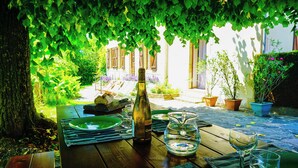An outdoor dining area with a table set for two, a bottle of wine, and a glass pitcher. - CHAMBERAT COUNTRY HOUSE (Chambérat)
