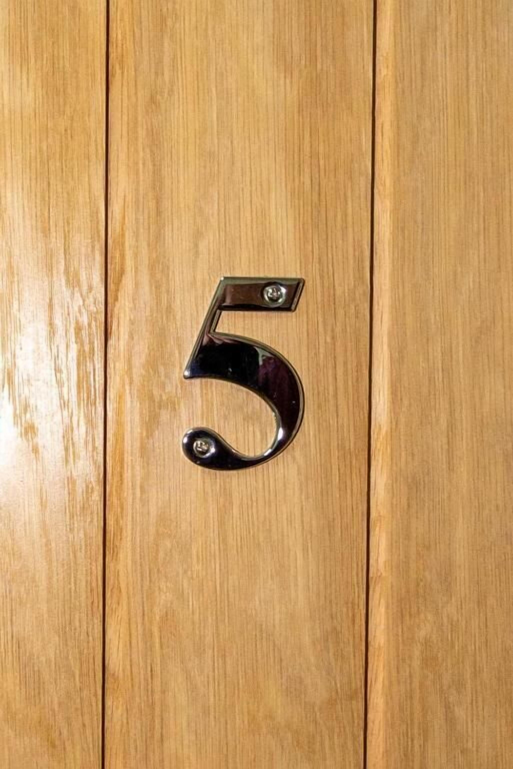A wooden door with a metallic number '5' handle.