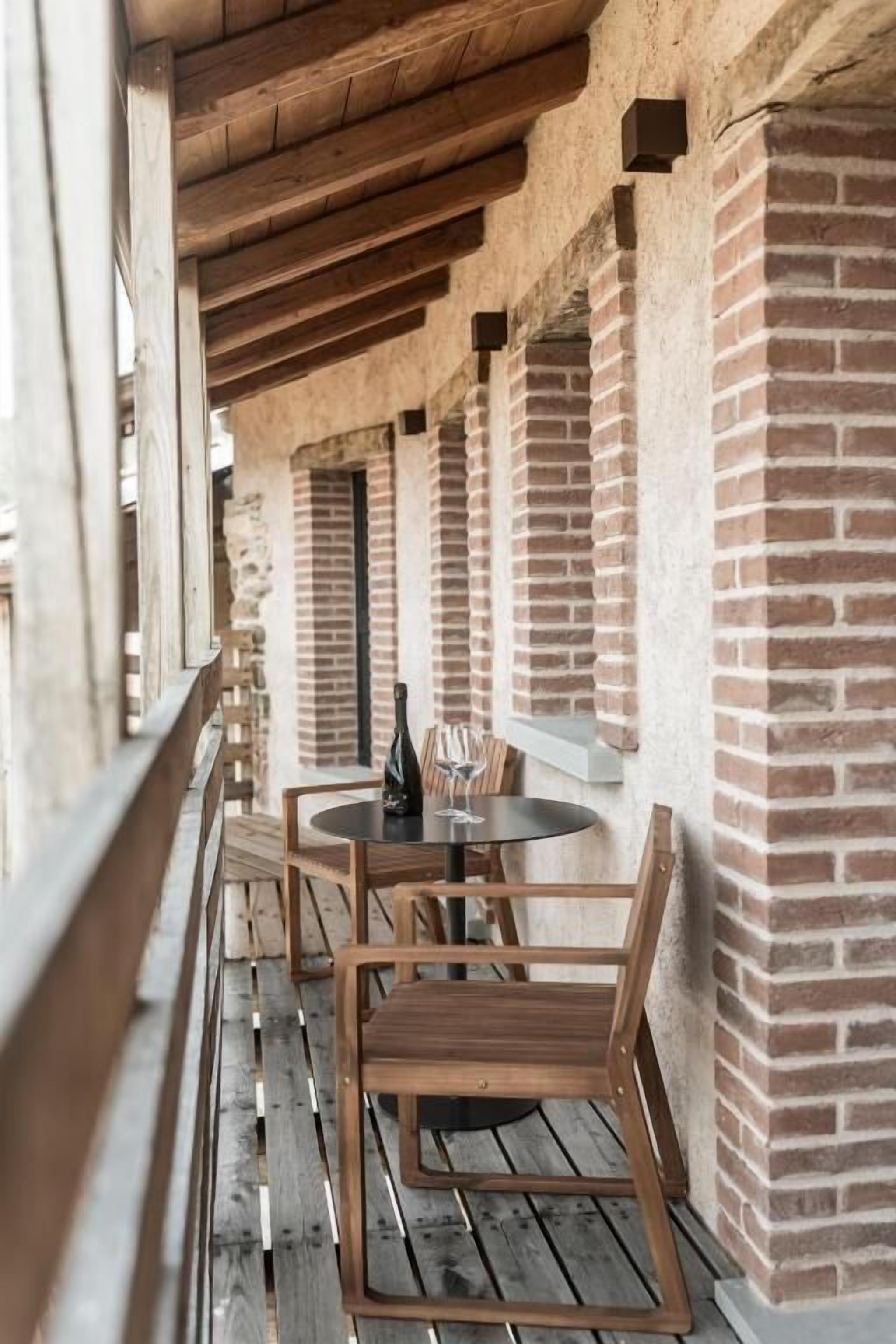 A wooden deck with a table and chairs, brick walls, and a wooden ceiling.