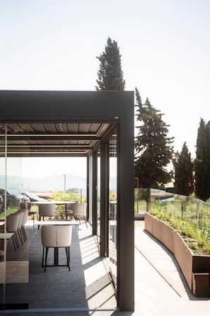 Un patio exterior moderno con cerramiento de vidrio, zona de estar y vistas al paisaje.