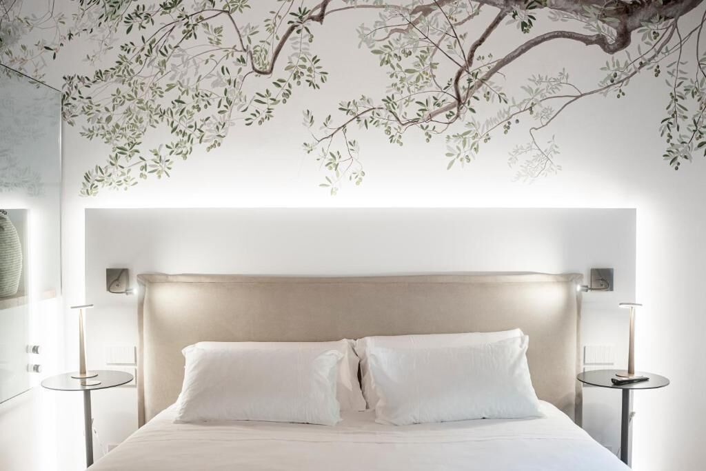 Un dormitorio con una cama grande, dos mesitas de noche y un mural en la pared.