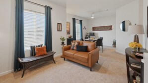 Ein Wohnzimmer mit einer Couch, einer Bank, einem Essbereich und einer Küche im Hintergrund.