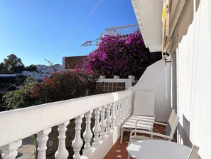 A balcony with white balustrades, a white table, and chairs. - Apartment in Nerja Near Burriana Beach (Nerja)