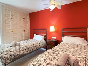 A hotel room with two beds, a ceiling fan, a nightstand with a lamp, and a wardrobe. - Apartment in Nerja Near Burriana Beach (Nerja)