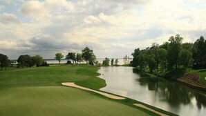 A golf course with a water hazard, sand bunkers, and a spectator area.
