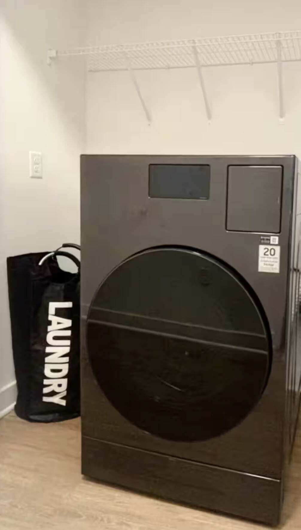 Een grote, donkere wasmachine met voorlader, bedieningspaneel en een klein beeldscherm.