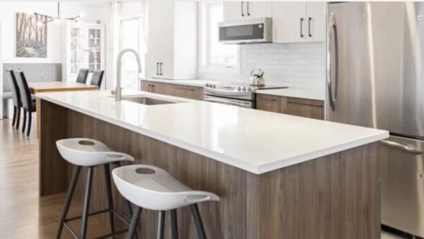 A modern kitchen with a large island, stainless steel appliances, and bar stools.