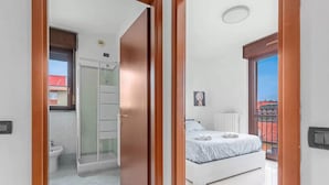 Ein Schlafzimmer mit Bett, ein Badezimmer mit Dusche und ein Balkon mit Blick.