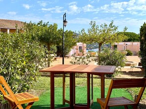 Ein Holztisch und zwei Stühle in einem Garten mit Blick auf Gebäude und Bäume.