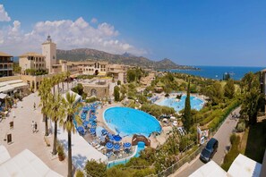 Ein Resort mit mehreren Schwimmbecken, einem zentralen Gebäude mit einem Turm und Blick auf das Meer.