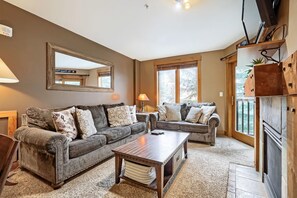 A living room with two sofas, a coffee table, a fireplace, and a large mirror on the wall. - 8836 The Springs 1 Bedroom Condo (Keystone)