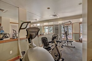 Ein Fitnessstudio mit Cardiogeräten, Gewichten und großen Fenstern.