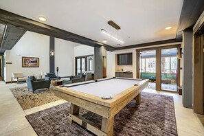 Une table de billard dans un salon moderne, avec vue sur l’extérieur.