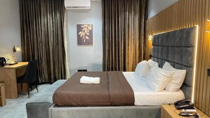 A modern hotel room with a large bed, a desk, and a chair. - Vogue Hotel (Karu)