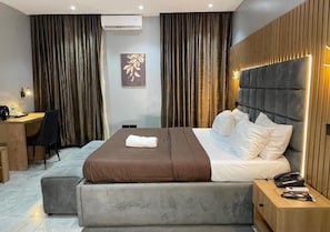 A modern hotel room with a large bed, a desk, and a chair. - Vogue Hotel (Karu)