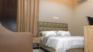 A modern bedroom with a bed, a nightstand, a chair, and a wooden dresser. - Vogue Hotel (Karu)