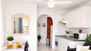 Una cocina moderna con armarios blancos, encimera negra y un microondas.