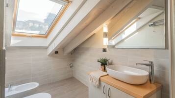 A modern bathroom with a skylight, a large vessel sink, and a mirror.