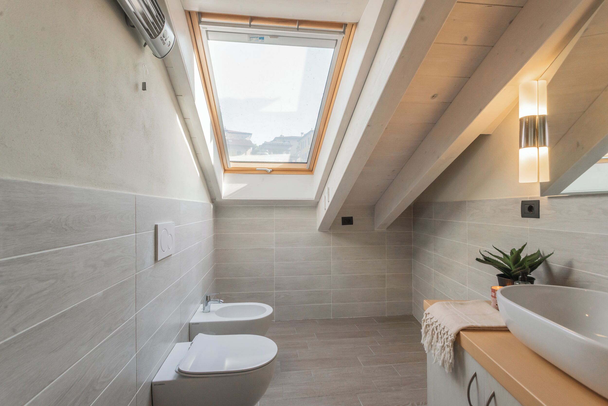 A modern bathroom with a skylight, a freestanding bathtub, a sink, and a mirror.
