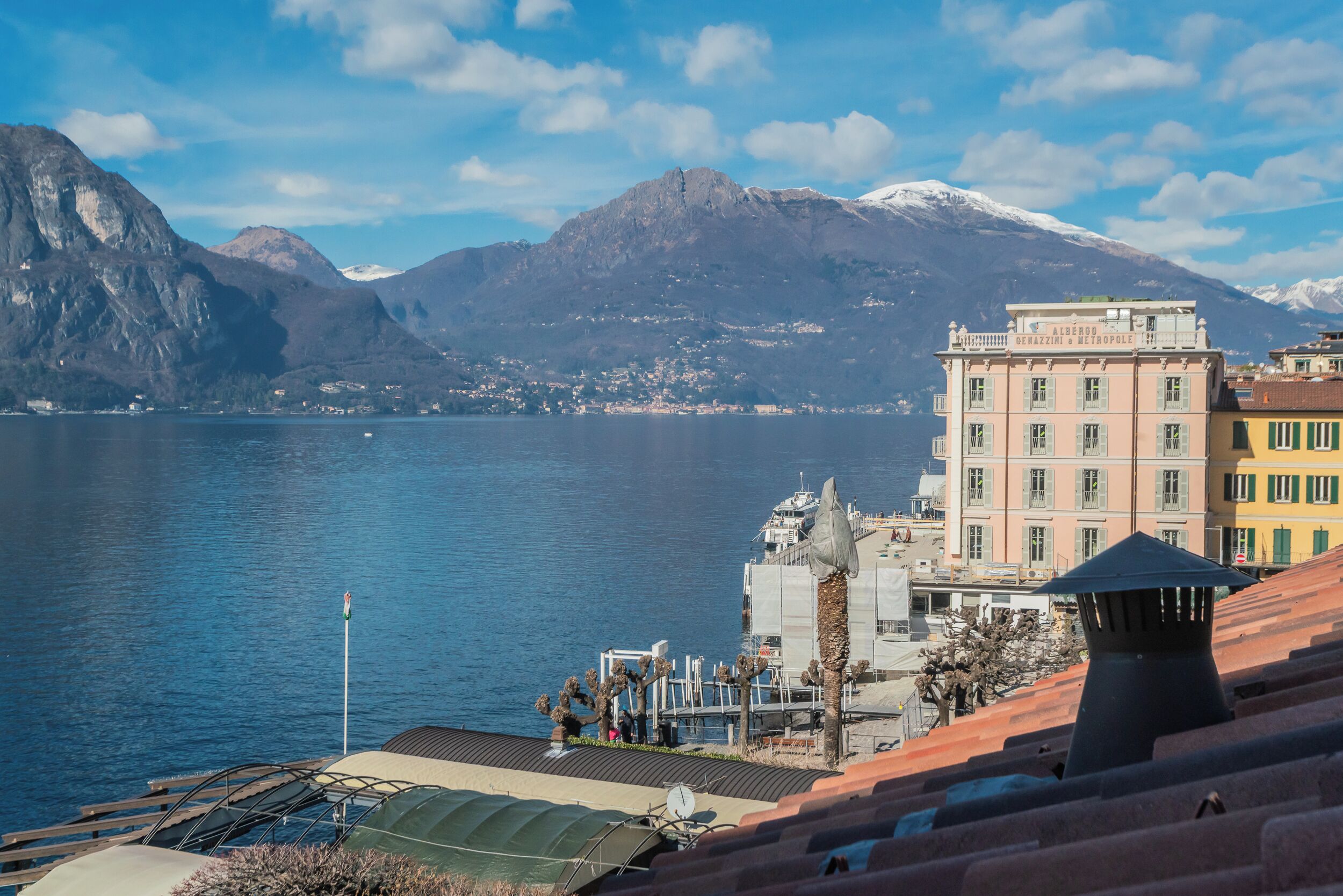 A coastal town with a mountain backdrop, a body of water, and buildings with balconies.