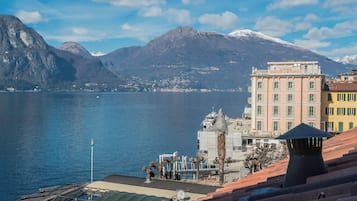 A coastal town with a mountain backdrop, a body of water, and buildings with balconies.