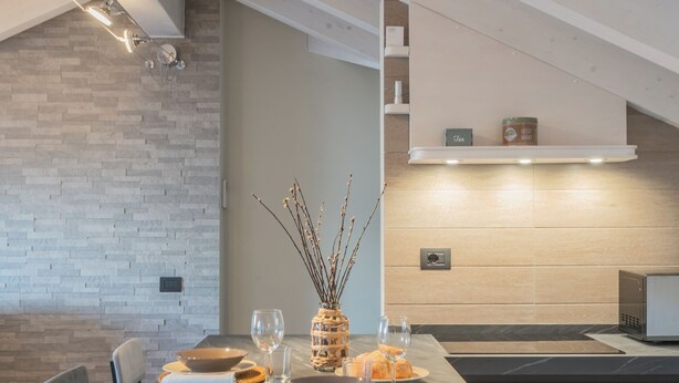 Una cocina moderna con una mesa de comedor para dos personas, horno empotrado y una pared de madera.