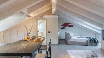 Un dormitorio tipo loft moderno con techo inclinado, una cama y un comedor con mesa y sillas.