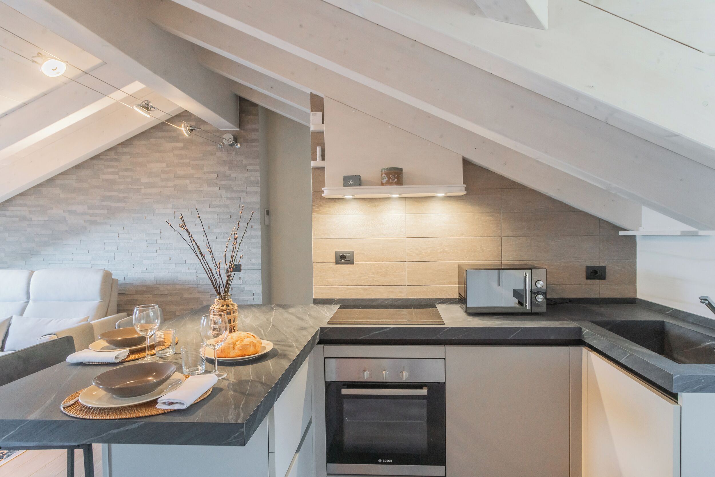 Una cucina moderna con un forno Bosch, una lavastoviglie integrata e un'area pranzo con tavolo apparecchiato per due.