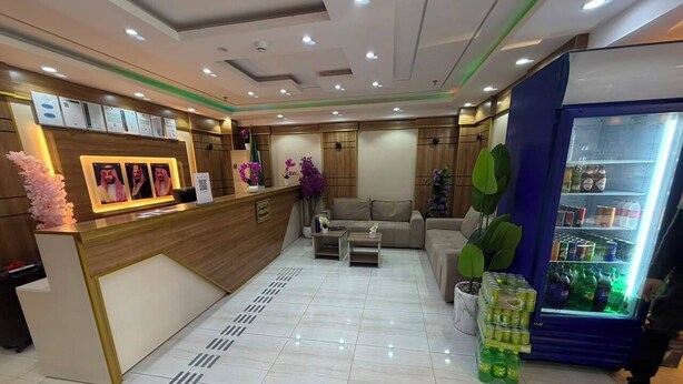 A hotel reception area with a reception desk, seating area, and a refrigerator stocked with beverages. - MEHAD MADINAH QUBA (Madinah)