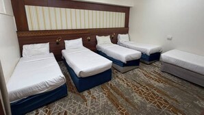 A hotel room with four single beds, a large striped headboard, and a patterned floor. - MEHAD MADINAH QUBA (Madinah)