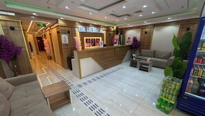 A hotel lobby with a reception desk, seating area, and a refrigerator stocked with beverages. - MEHAD MADINAH QUBA (Madinah)