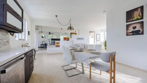 Een moderne keuken met een eethoek, witte wanden en een plafondventilator.