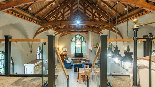 A spacious loft with high ceilings, exposed wooden beams, a large window, and a dining area. - Grade C Church in Cannich, Sleeps 2 w/ Parking (Beauly)