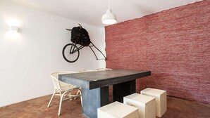 A dining area with a table, chairs, and a wall-mounted bicycle. - Cheese&Wine™ | Alfama - Sto. Estevão Viewpoint 2 (Lisboa)