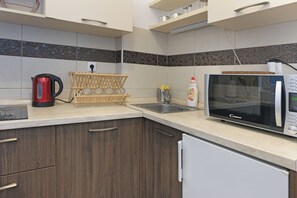 A kitchen with a microwave, kettle, and a wooden rack holding glasses. - Balkanska Central Residence (Beograd)