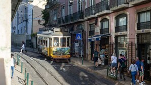 Eine Straßenbahn fährt auf einer Straße mit Fußgängern und Gebäuden mit Balkonen.