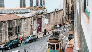 Una calle estrecha con tranvía, edificios y automóviles estacionados.