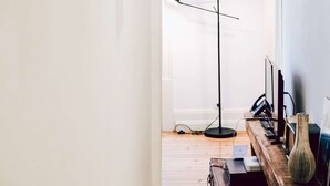 Una habitación con escritorio, lámpara, un jarrón y cuadros en la pared.
